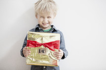 A child holding a Christmas gift for Dad