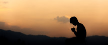silhouette of an individual with praying hands 