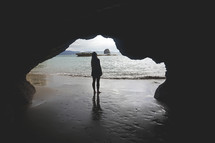 woman standing in a cave on a beach 