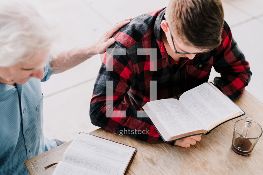 mentor reading a Bible with a man at a Bible study 