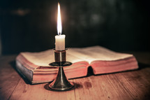 candlelight from a candle stick and an open BIble