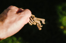hand holding set of old keys against grassy backdrop