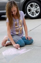 girl drawing a heart in sidewalk chalk 