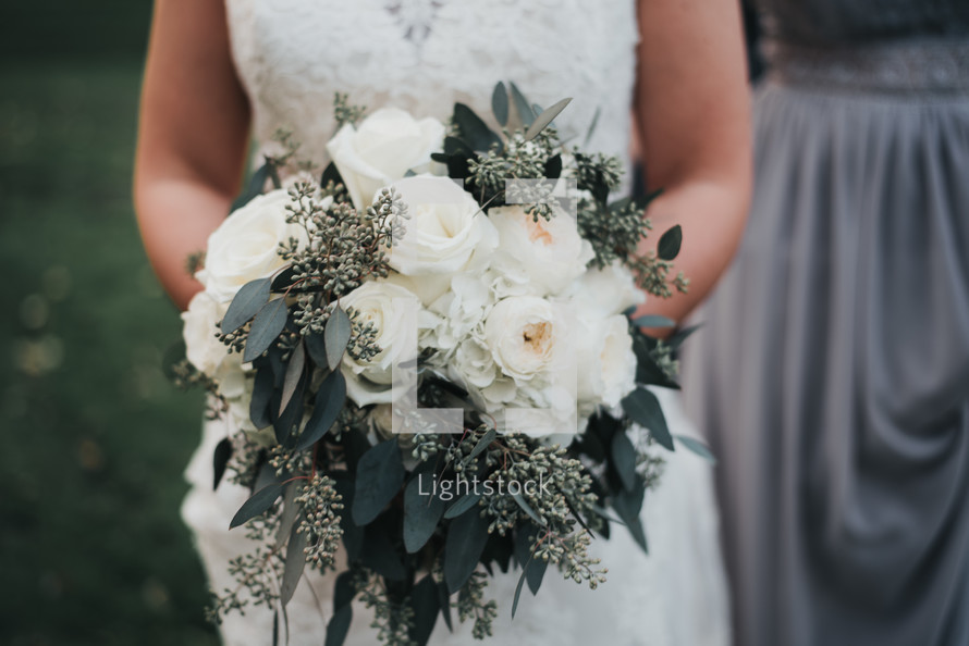 bride holding a bouquet of white roses 