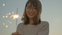 a young woman holding a sparkler