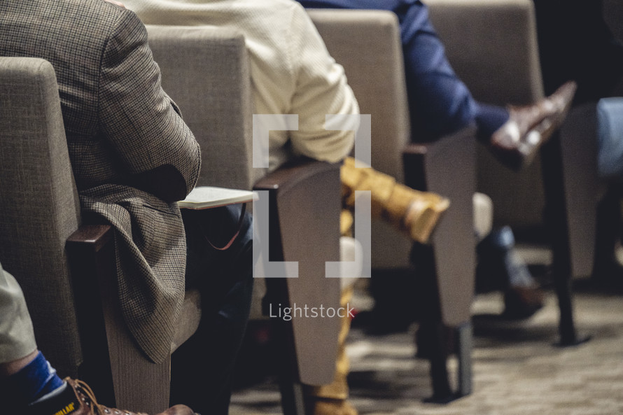 Close up of people's legs sitting in a church worship service.