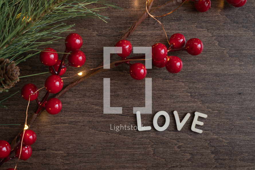 red berries and fairy lights on a wood background and word love 