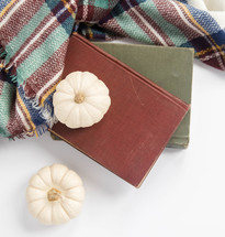 white pumpkins, books, and plaid shawl 