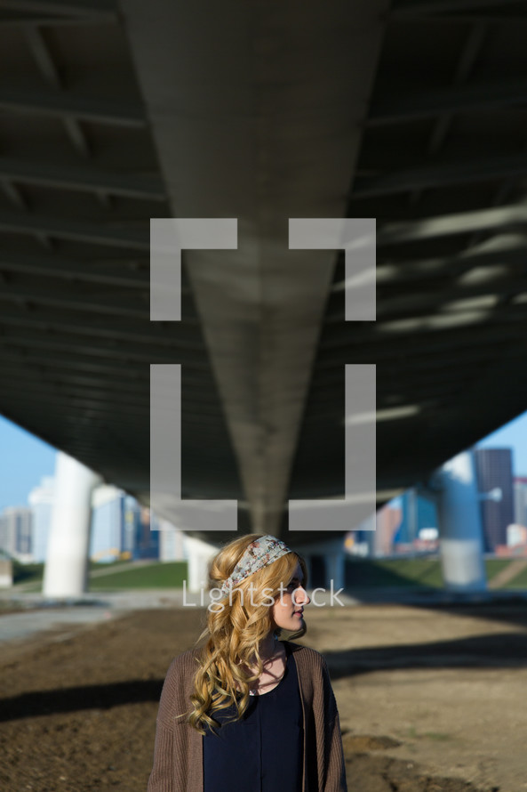 side profile of a woman standing under an overpass 