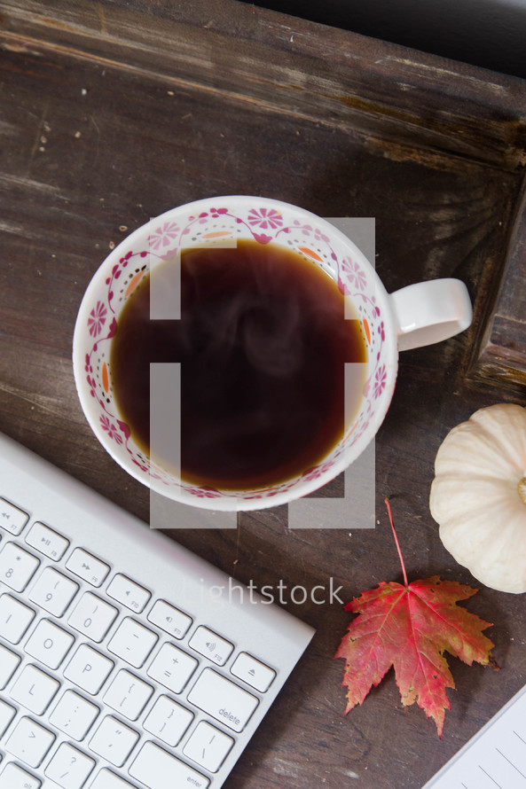 steaming mug of coffee and computer keyboard in fall 