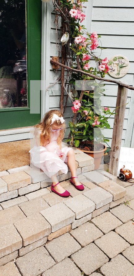 girl in a fancy dress sitting on steps praying 