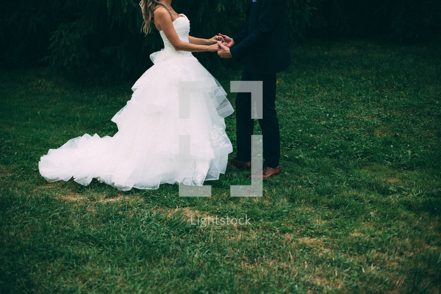 bride and groom holding hands standing in grass 
