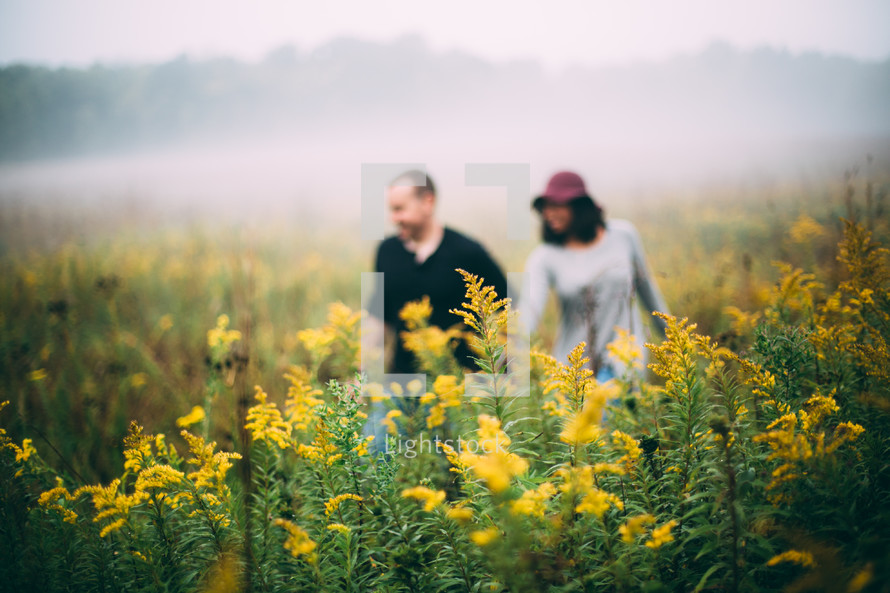 a couple walking through a field of wildflowers