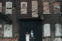 a bride and groom in front of a brick warehouse building 