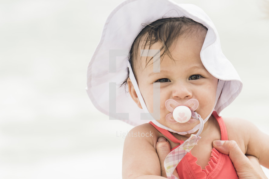 a baby on a beach with a pacifier 