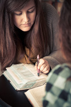 young woman pointing to scripture in a Bible