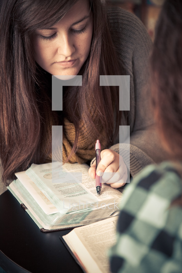 young woman pointing to scripture in a Bible