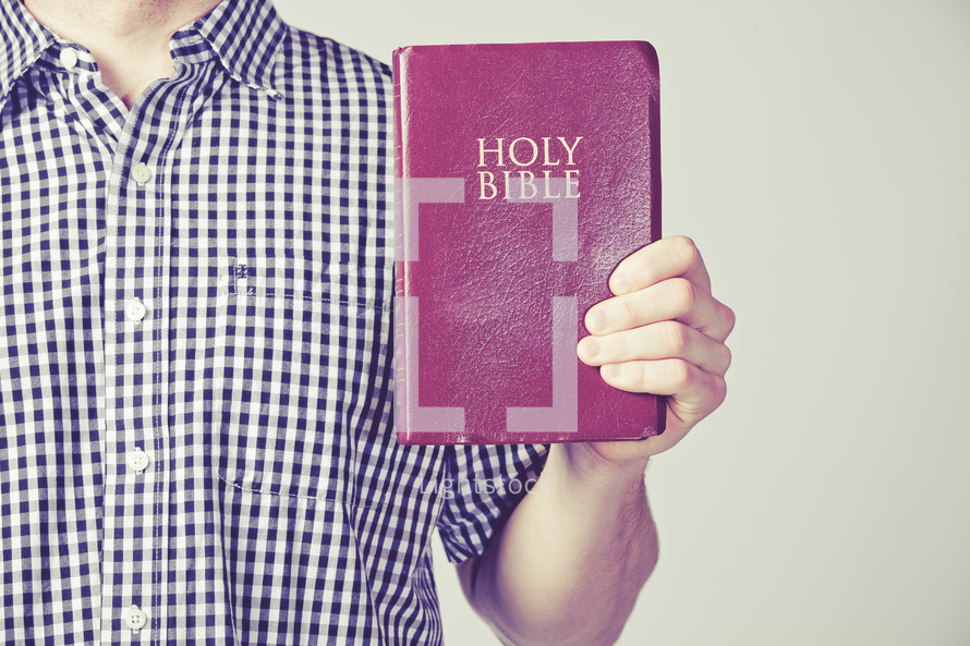 man holding out a red covered Holy Bible