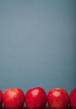 A line of red apples on a blue background.