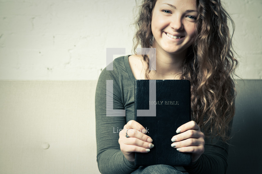 teen girl holding a Bible and smiling 