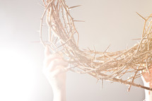 hand lifting up a crown of thorns