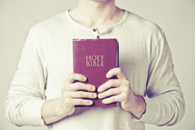 man holding a red Holy Bible