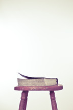 Closed Bible on top of wooden stool. 