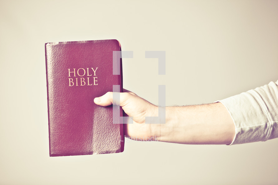 man holding a red covered Bible