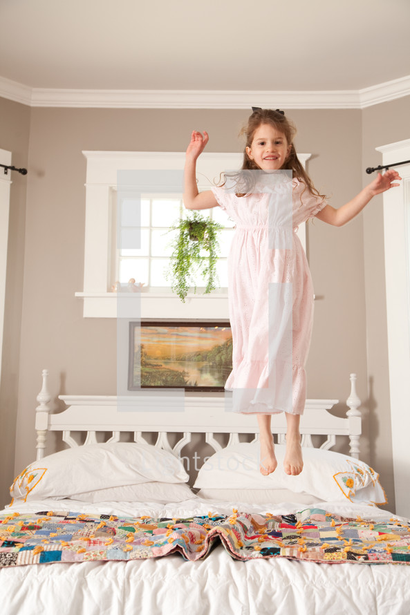 little girl jumping on a bed