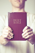 man holding a red Holy Bible