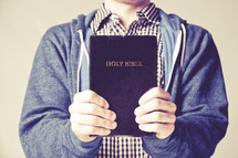 man holding up a black Holy Bible