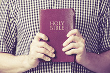 man holding up a red Holy Bible
