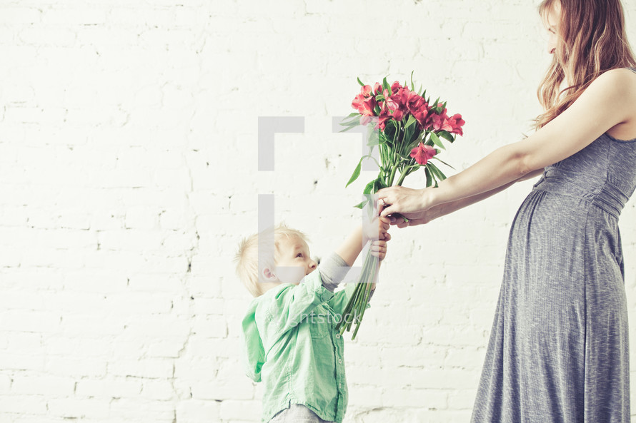 son handing his mother a bouquet of flowers