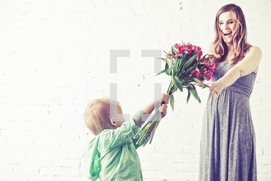 Boy giving bouquet of flowers to his mother.