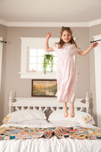 little girl jumping on a bed