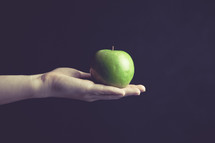 hand holding out a green apple
