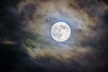 The moon peeking through the cloud at night.