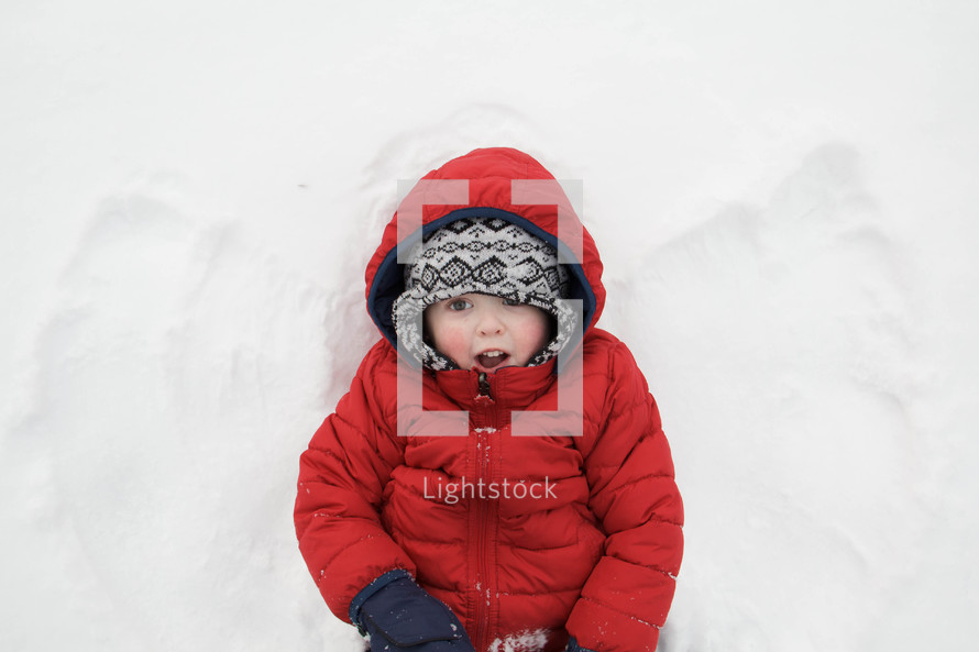 child making snow angels in the snow 