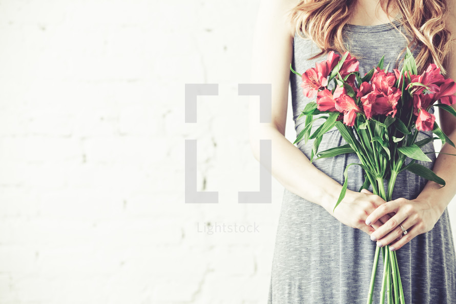 Pregnant woman holding bouquet of flowers.