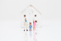 figurines of a family standing in front of a house 