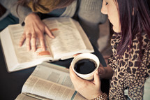 young woman holding a cup of coffee as she read and discusses scripture at a Bible study