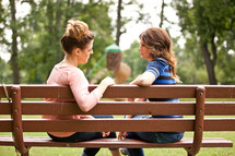 women in conversation on a park bench 