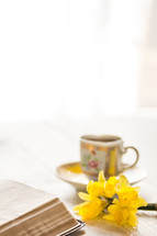 a cup of coffee with a Bible and flowers