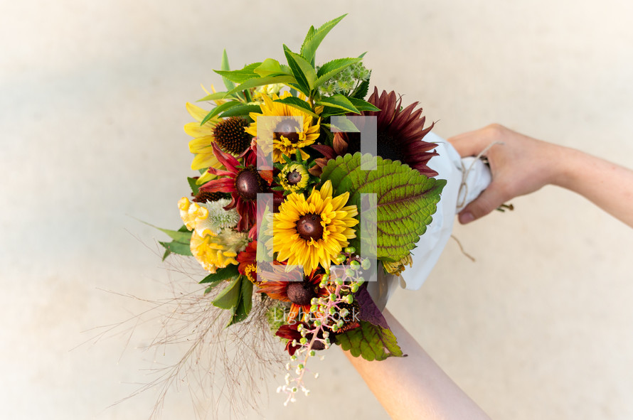 a woman holding a fall flower bouquet 