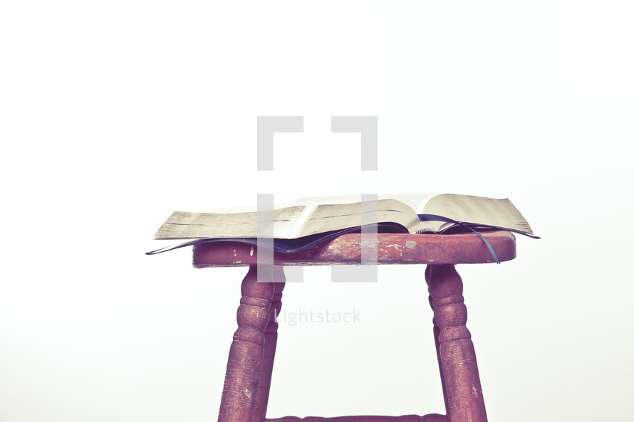 Open Bible on top of wooden stool.