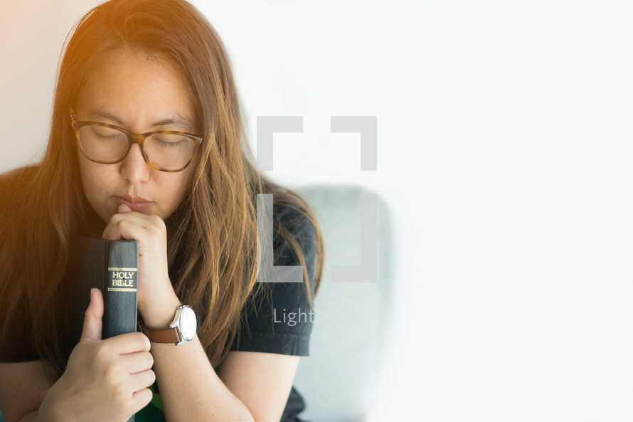 teen girl praying holding a Bible 