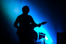 silhouette of a man on stage playing a guitar 