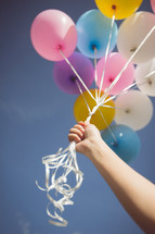 hand holding helium balloons 