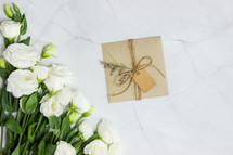 white roses and gift wrapped in brown paper 