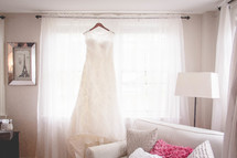 a wedding dress hanging in a window 